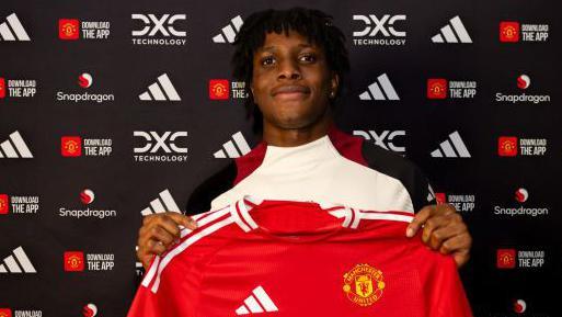 Patrick Dorgu holding up a Manchester United shirt