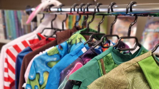 A metal rail with black wire hangers across it, holding various children's dress up costumes.