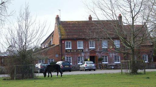 A pony grazes in front of The Alice Lisle, a two-storey brick pub.