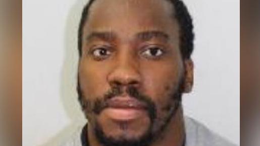 Kamar Williams. He has close cropped black hair and a beard. He is wearing a grey top