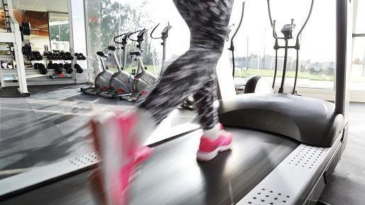 The picture shows the legs of a women in leggings and pink trainers on a treadmill