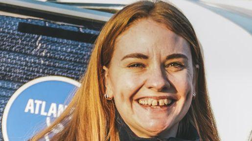 Sophie Pierce smiling at the camera, she has long blonde hair and is wearing small hoop earrings. 