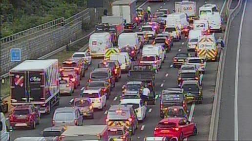 Four rows of bumper-to-bumper traffic being held on a motorway. The vehicles are facing away from us.