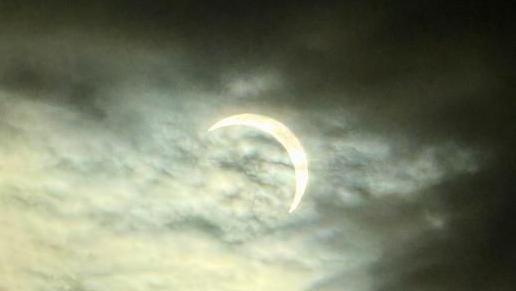 solar eclipse partially covered by clouds 