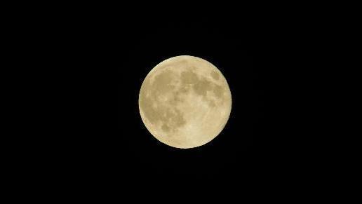 A large yellowish moon against a black background