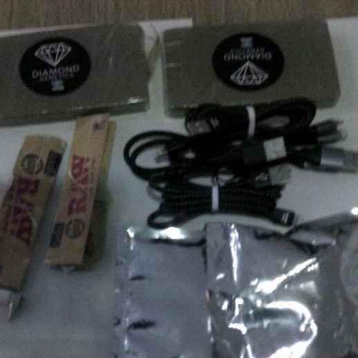 Some rolling papers, two packages and some cables laid out on a table