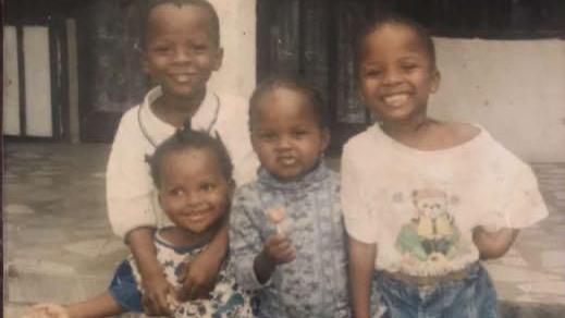 Family photograph showing four young children standing close together and smiling