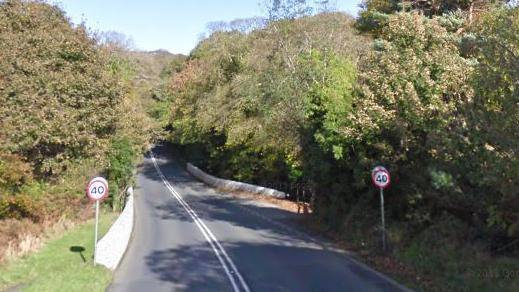 Whitebridge Road heading out of Onchan on the A2. There are low white walls thick bushes and trees on either side of the road along with 40mph road signs.