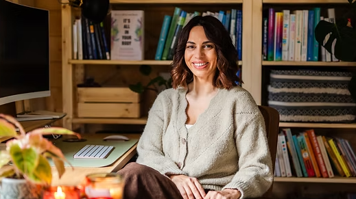 Sula in her office surrounded by books, candles and a plant