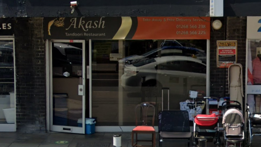 The outside of the Akash Tandoori, a restaurant with a glass door and a large glass window with a sign above saying "Akash".