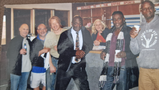 Mr Russell is standing at a bar with his training partners. He is wearing a black jacket and a tie. 