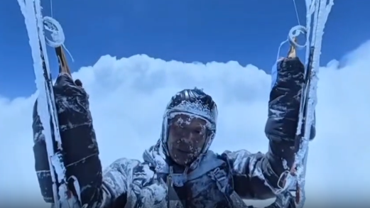 Chinese paraglider covered in ice, high up in the clouds