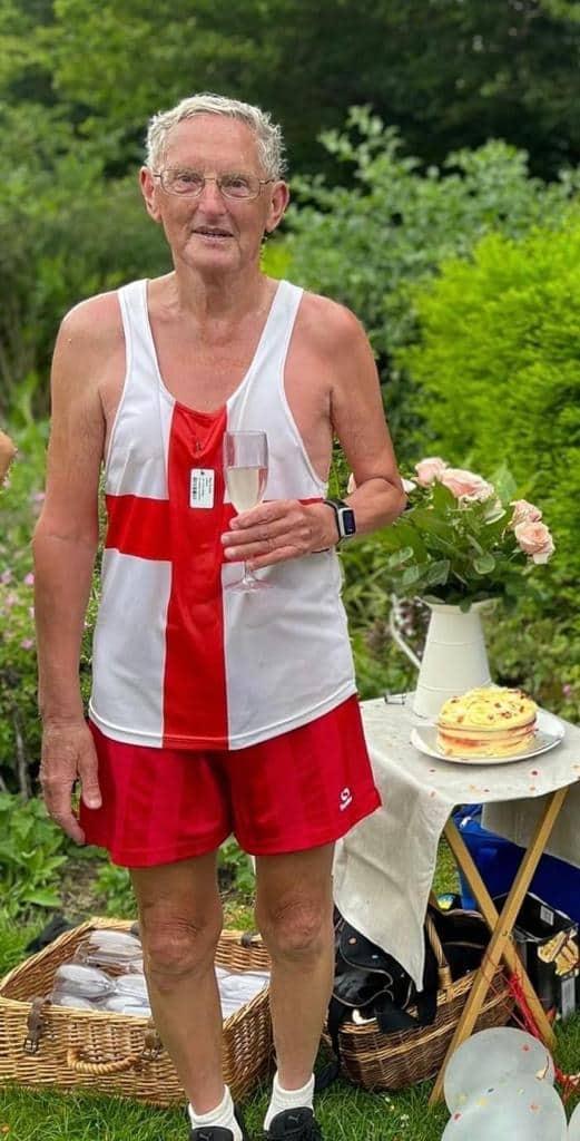 Ray Evans holding a drink and standing by a cake 