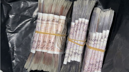 Bundles of cash lie on top of a plastic sheet