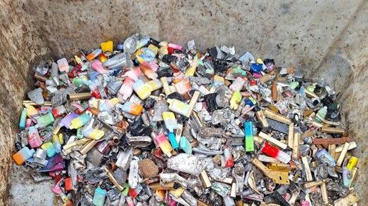 A large quantity of different coloured vapes in a large bin