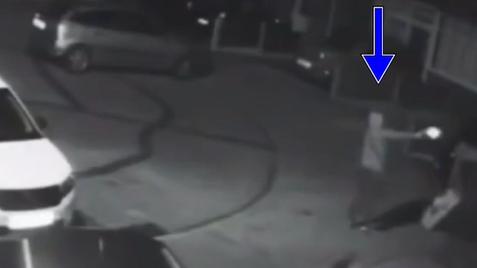 Black and white footage captures Betro standing and firing at the house in the cul de sac 