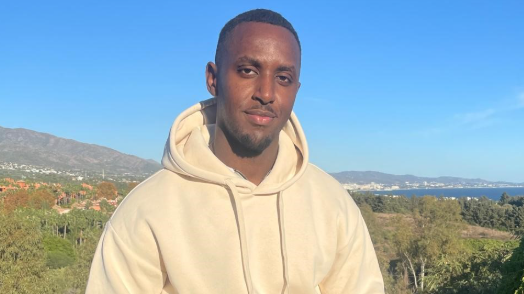 Frederick Mutala looking at the camera is wearing a beige hoodie.