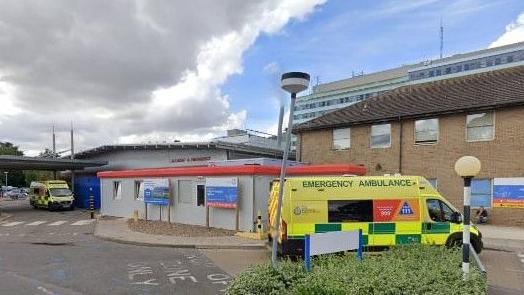 A Google street view on hospital premises. An emergency ambulance van which is yellow and green is parked to the side with a building in the distance that says 'accident and emergency'.