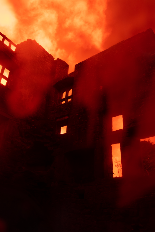 A silhouette of Lanercost Priory. The tones of the photo are dark red, giving it a spooky feel. 