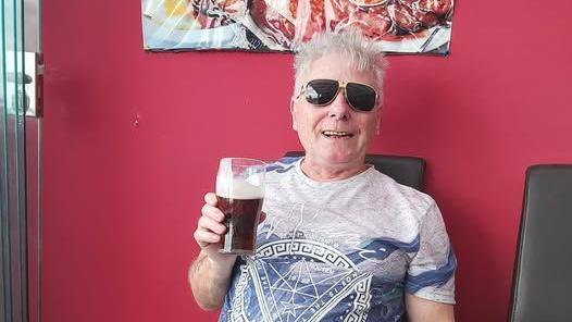 A photo of a man with white hair holding a pint.