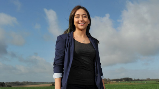 A photo showing Dr Karen Rial Lovera from The Royal Agricultural University stood outside with blue sky and clouds in the background