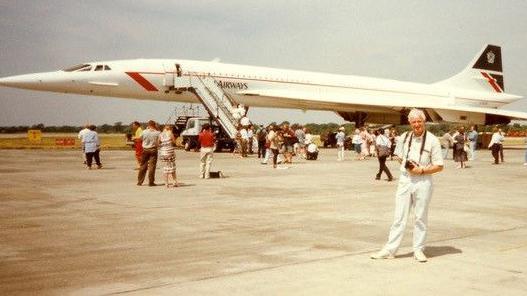 A large Concorde aircraft with many people standing around it on a runway.