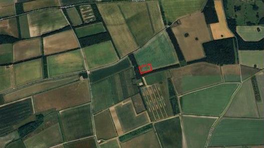 An aerial view of the proposed siting of the slurry pit is outlined in red. The site is surrounded by fields.
