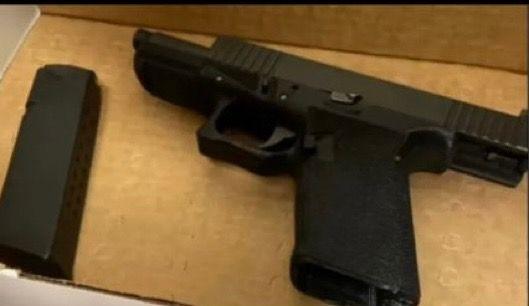 A black handgun with a clip removed is seen as evidence