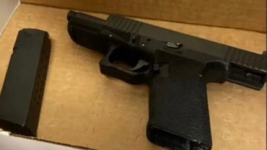 Picture of a gun  that was found with Luigi Mangione. It is a pic of a black gun with a clip on the left of it. It appears to be on a piece of brown cardboard 