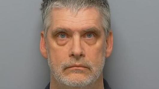 Matthew Myatt custody photo. He has a grey short beard, grey hair and light coloured eyes