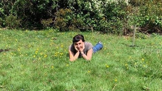Sonia Rosenblatt lying on the grass at the nature reserve next to the trees that were planted