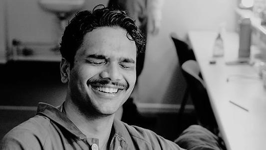 Rithvik Andugula has his eyes closed and seems to be laughing. He is sat at what seems to be a mirrored dressing table.