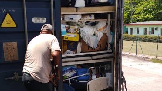 A man in a cap is unloading a container of supplies in cuba.