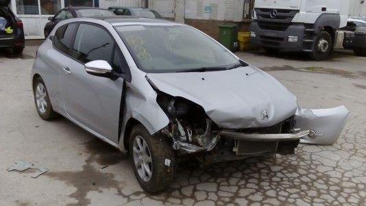 A silver Peugeot 208. The front bumper of the car is smashed up, following a collision.