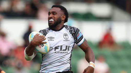 Joji Nasova playing rugby sevens for Fiji with the ball in his right arm