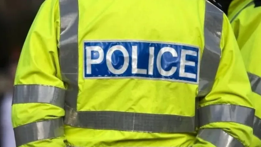 The back of a police officer wearing a high-vis jacket with police written on it