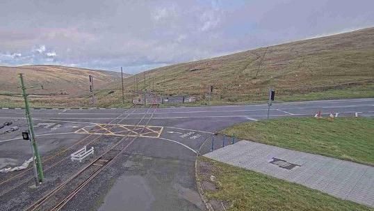 The Mountain Road at the junction at the Bungalow showing the electric tram tracks and other infrastructure with the hills sloping into the Laxey Valley behind.
