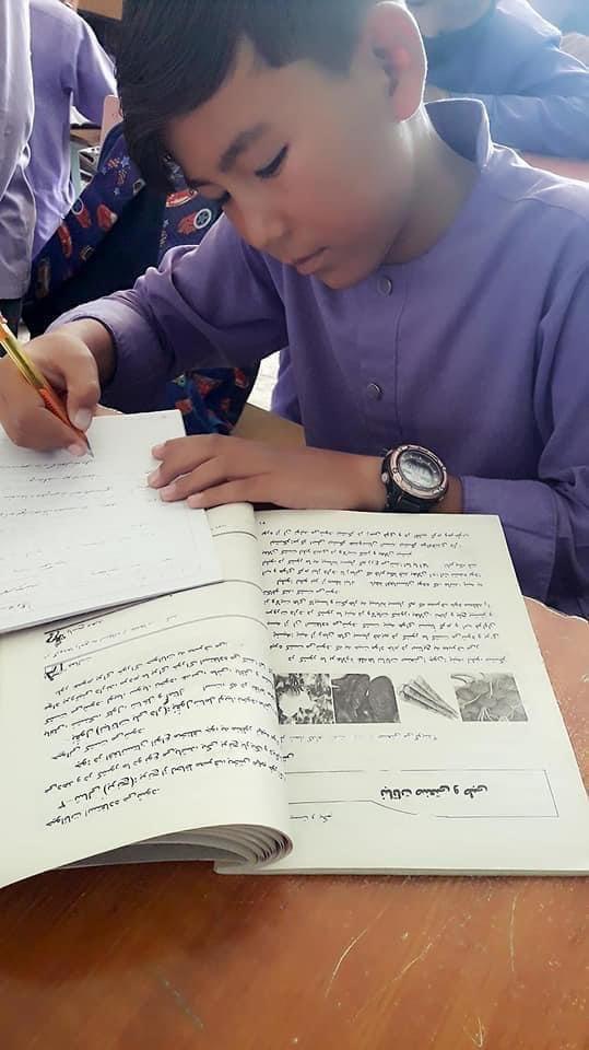 Ahmad-writing-in-school-book.