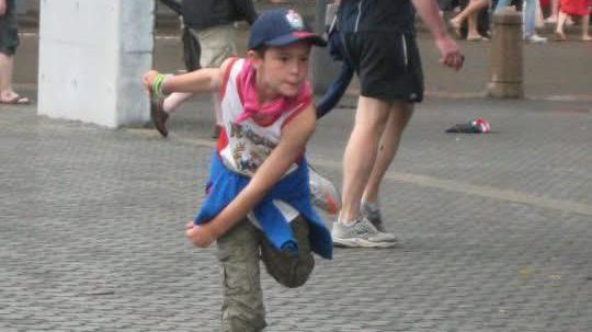 A young Josh Baker bowls on the concourses beside the stands at a Test match