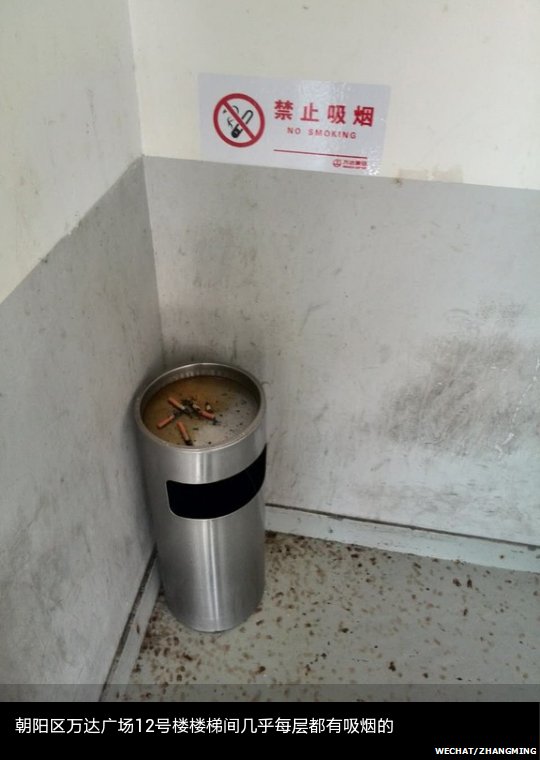 A WeChat photo of cigarettes on a trash bin on a stairwell with a "No Smoking" sigh