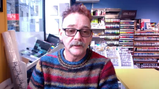 Greg Baker, owner of Craft and Canvas,  wearing a stripy woolly jumper talking into a laptop camera