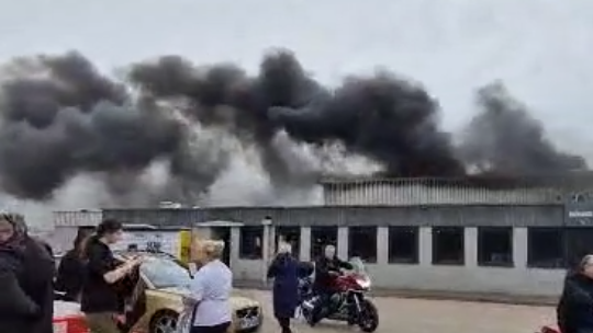 Black smoke billows from an industrial grey building.