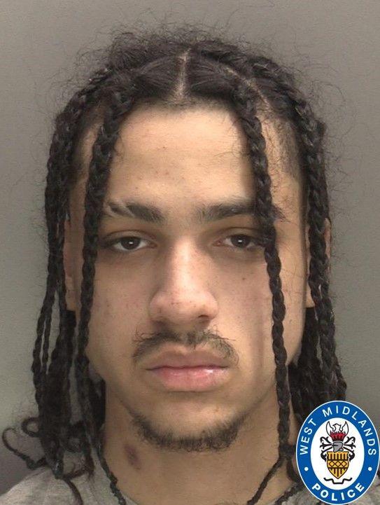 A police photo of a man with black dreadlocks, and a slight beard and moustache.