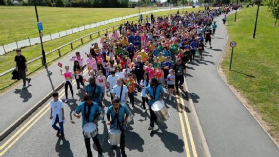 A parade led by steel drummers followed by hundreds of school children