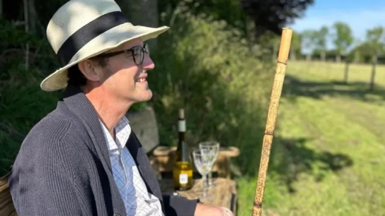 Simon Boas, sitting looking at a field in the sunshine