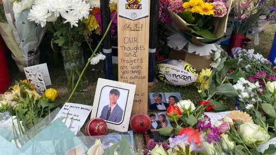 Flowers and cards left at Barnaby Webber's funeral, with photographs of him dressed in a suit.  