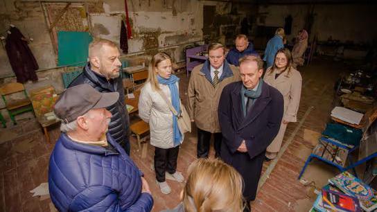 A group in a basement. You can see tables and chairs scattered around the room