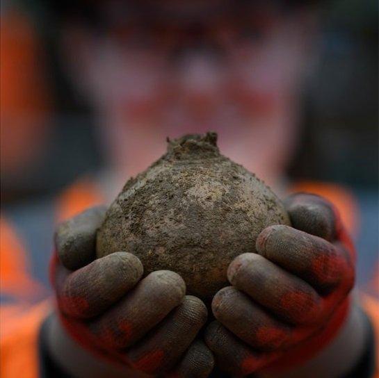 an archaeologist holds up a pot covered in mud