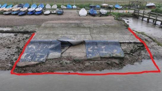 A grey concrete slipway showing signs of erosion, cracks and damage has been outlined in red on the photograph to highlight the area needed to be repaired