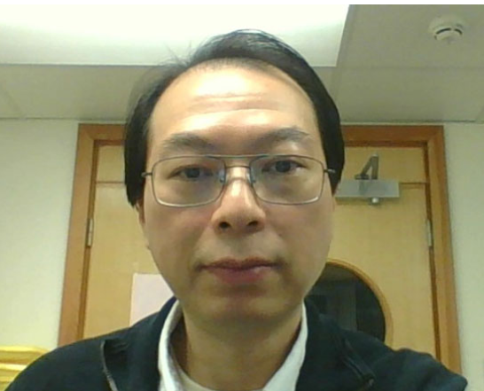 Dr Thong Cao wearing glasses with short hair in front of a wooden door.